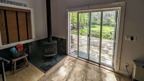 Quarto com lareira, porta de correr para um deck e um letreiro com a palavra 'MAINE'.