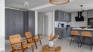 A modern kitchen with grey cabinets, a black countertop, and a hanging light fixture. - Modern Elegance/Private Pool (Fuengirola)