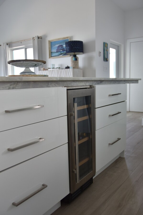 Una cocina moderna con armarios blancos, lavavajillas integrado y encimera de mármol.
