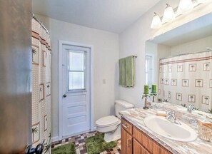 Bathroom features a toilet, sink, and shower area with a patterned curtain.