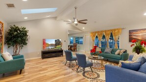A spacious living room with a large flat-screen TV, a ceiling fan, and a dining area with a table and chairs. - Cozy&Tranquil Heaven With KingSuite&Covered Patio&BigFencedYard, 5-Star-Location (Austin)