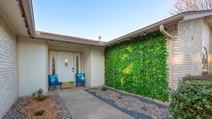 A building with a green wall, a door, and two blue chairs outside. - Cozy&Tranquil Heaven With KingSuite&Covered Patio&BigFencedYard, 5-Star-Location (Austin)