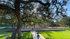 A park with a walking path, playground equipment, and a large tree providing shade. - Cozy&Tranquil Heaven With KingSuite&Covered Patio&BigFencedYard, 5-Star-Location (Austin)