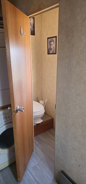 A bathroom with a toilet, a wooden door, and a small framed picture on the wall. - Roswell Alien Retreat: Stargazing, 80-Acre Ranch, Pet-Friendly Near UFO Museum (Dexter)