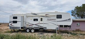 Een witte camper met 'DURANGO'-aanduiding geparkeerd in een landelijk gebied.