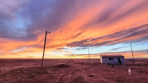 A rural landscape with a small house and a dirt road.