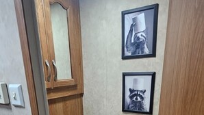 A bathroom with a toilet, wooden cabinet, and two framed pictures on the wall.