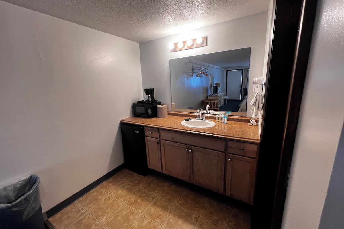 A hotel bathroom with a sink, mirror, and a coffee maker.