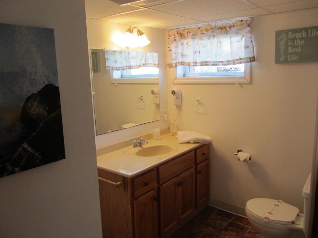 A bathroom with a sink, mirror, vanity, and toilet.