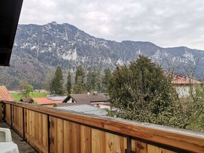 A wooden balcony overlooking a mountainous landscape with houses and trees. - Ferienwohnung für 2 bis 4 Personen, 2 Schlafzimmer, Balkon, 64 m² (Inzell)