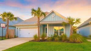 Une maison de plain-pied avec un garage, entourée d’une pelouse bien entretenue et de palmiers.