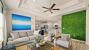 Un salon moderne avec un canapé, des fauteuils, une table basse et un mur vert.