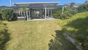 A modern building with a covered outdoor seating area and a grassy lawn. - Just ONE Minute TO Medlands Beach (Auckland)
