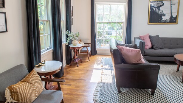 A living room with a sofa, armchair, and a small table with a vase. - J Birds' Cottage in the heart of Midtown  (Memphis)