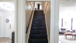 A staircase with a handrail leading to a living area with a sofa and a coffee table. - J Birds' Cottage in the heart of Midtown  (Memphis)