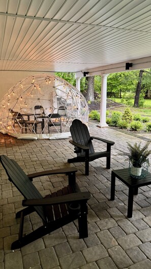 An outdoor patio with a covered seating area, a table with chairs, and a decorative glass sphere. - Estate 5BR 3.5Bath with IGLOO, Game Rm, Fire Pit sleeps 16- 5min Princeton dwtn (Princeton)