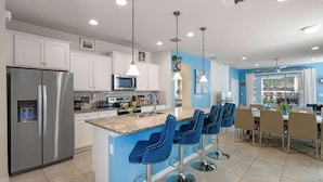 A modern kitchen with a central island, stainless steel appliances, and blue bar stools. - Fabulous 7 bed pool home, gated community with FREE ACCESS to resort facilities! (Kissimmee)