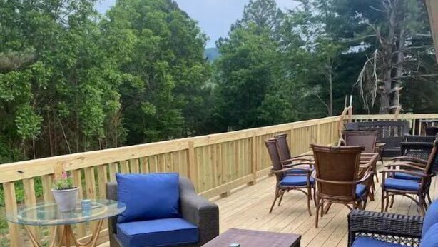 A wooden deck with outdoor furniture, including sofas and chairs, and a glass table. - Alice’s Acres (Valley Head)