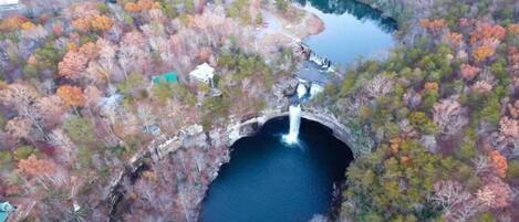 An aerial view of a bridge over a river surrounded by autumn-colored trees.