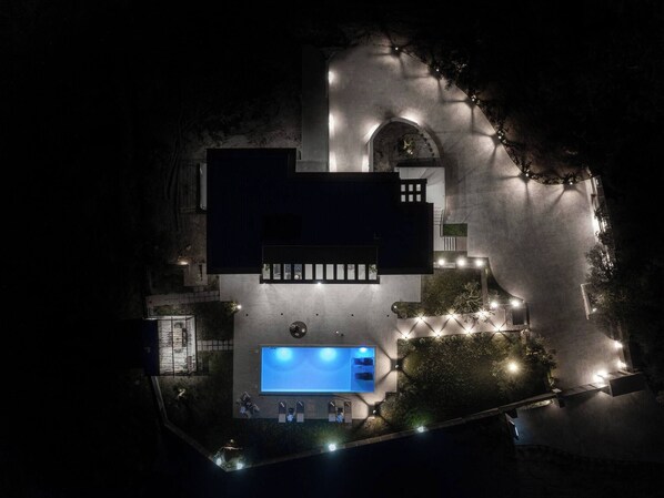An aerial view of a modern building with a swimming pool, multiple entry points, and surrounding landscaping.