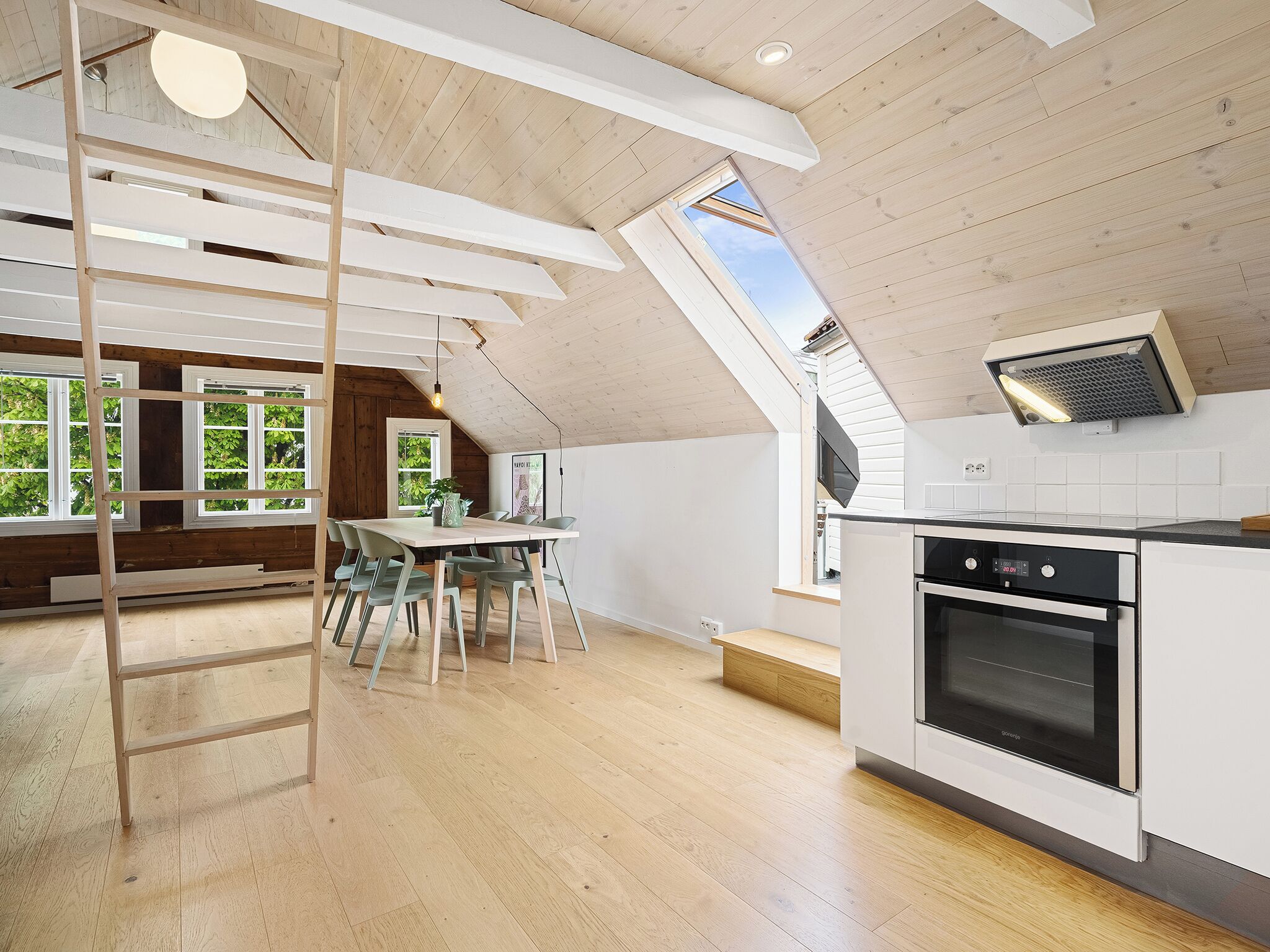 Une cuisine moderne dotée d’une verrière, d’un plafond en bois et d’un coin repas avec une table et des chaises.