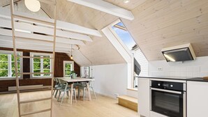 Une cuisine moderne dotée d’une verrière, d’un plafond en bois et d’un coin repas avec une table et des chaises.