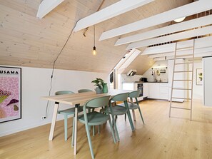 Une cuisine moderne avec un espace repas en mezzanine, des poutres en bois et une échelle.
