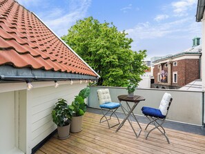 Un balcon doté d’un toit en tuiles, de plantes en pot et de mobilier d’extérieur.