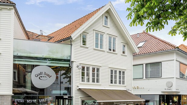 Un bâtiment avec une enseigne indiquant une boulangerie, des tables à l’extérieur et un pavage en pierre.
