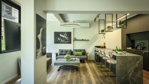 A modern kitchen with a marble island, bar stools, and a dining area with a sofa and coffee table. - Sophisticated Tel Aviv Retreat 1BR Apt (Tel Aviv)
