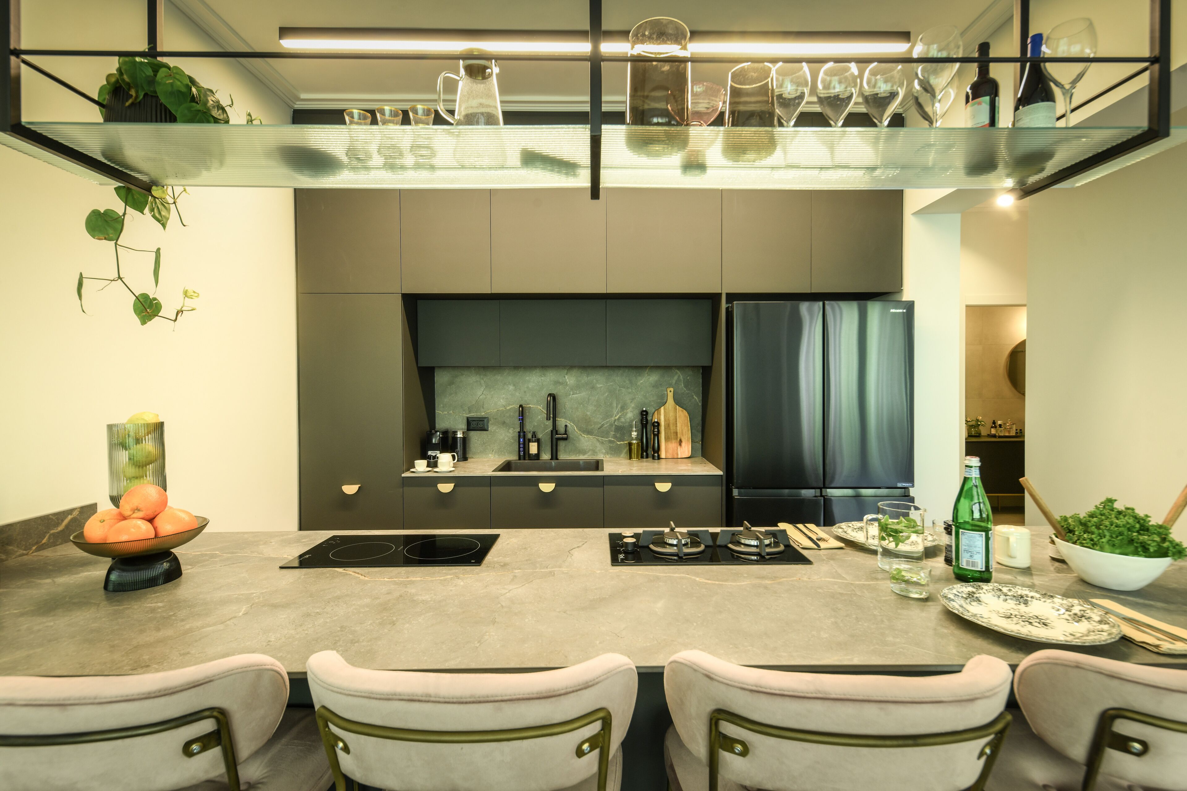 A modern kitchen with a central island, a built-in oven, and a refrigerator.
