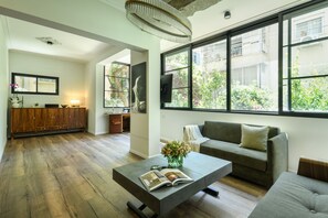 Una sala de estar moderna con un sofá, una mesa de centro y un ventanal con vistas a zonas verdes.