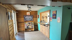A hallway with wooden walls, a carpet, and a display of books and magazines. - Badlands Motel Kadoka by OYO (Kadoka)