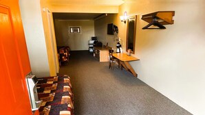 A narrow hallway with a patterned bench, a wooden table, and a television mounted on the wall. - Badlands Motel Kadoka by OYO (Kadoka)