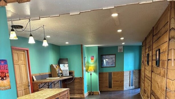 A spacious lobby with a wooden reception desk, a telephone, and a lamp. - Badlands Motel Kadoka by OYO (Kadoka)
