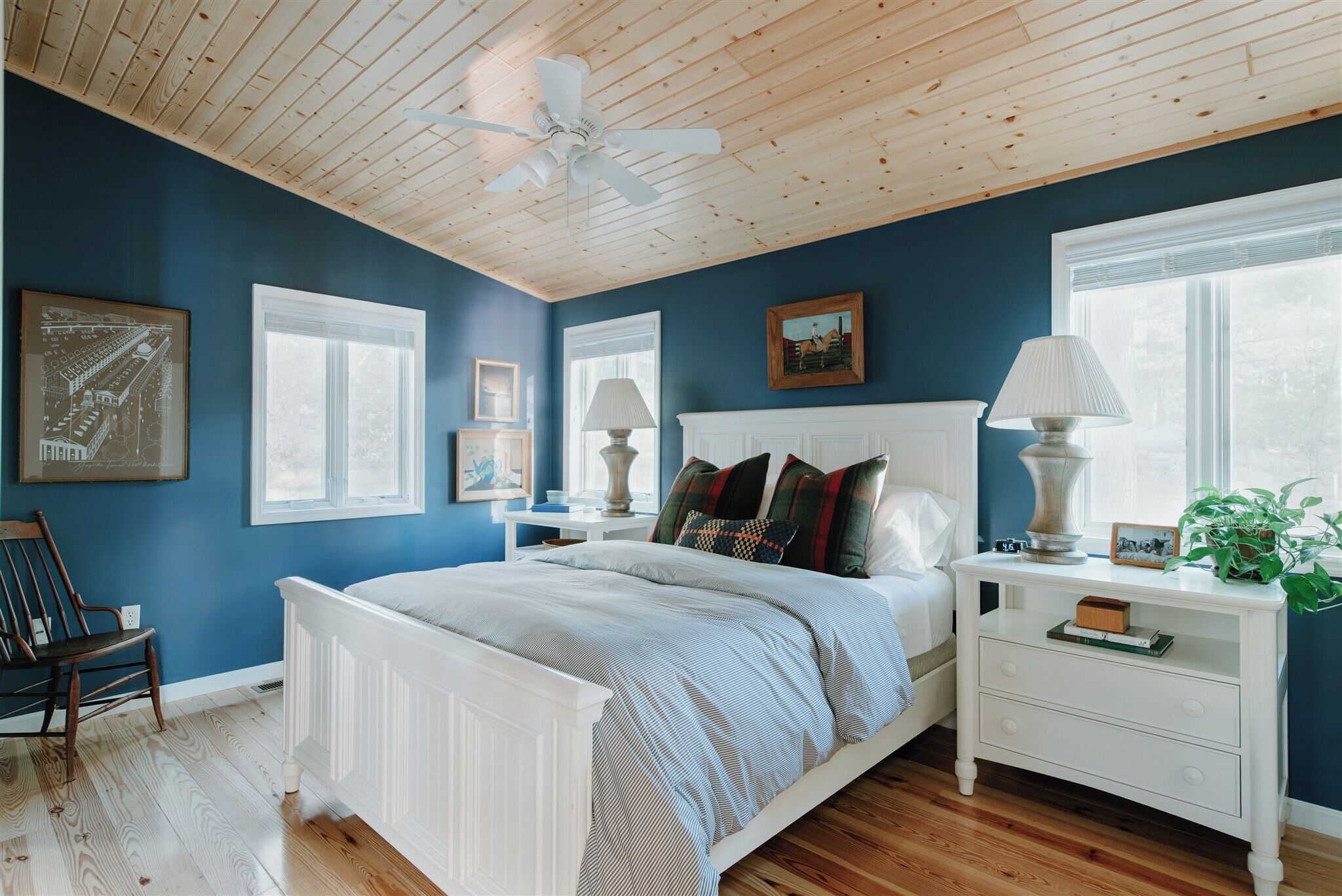 Une chambre avec un lit blanc, un plafond en bois et un mur bleu.
