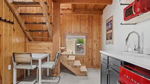 A wooden interior with a dining area, a kitchen with a red Galanz microwave, and a window with a view.