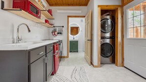 A modern kitchen with a wooden ceiling, a built-in oven, and a washing machine in a wooden cabinet.