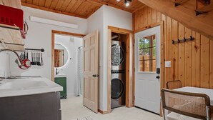 A laundry room with a washing machine and dryer, a sink, and a chair.