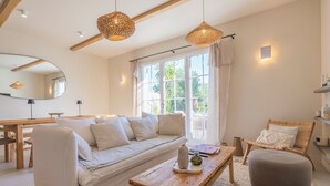 A modern living room with a sofa, wooden coffee table, and a wicker chair. - Villa Rénovée Avec Piscine et Amarrage, Dans Domaine Sécurité, Avec Plage à 5 mn (Port Grimaud)