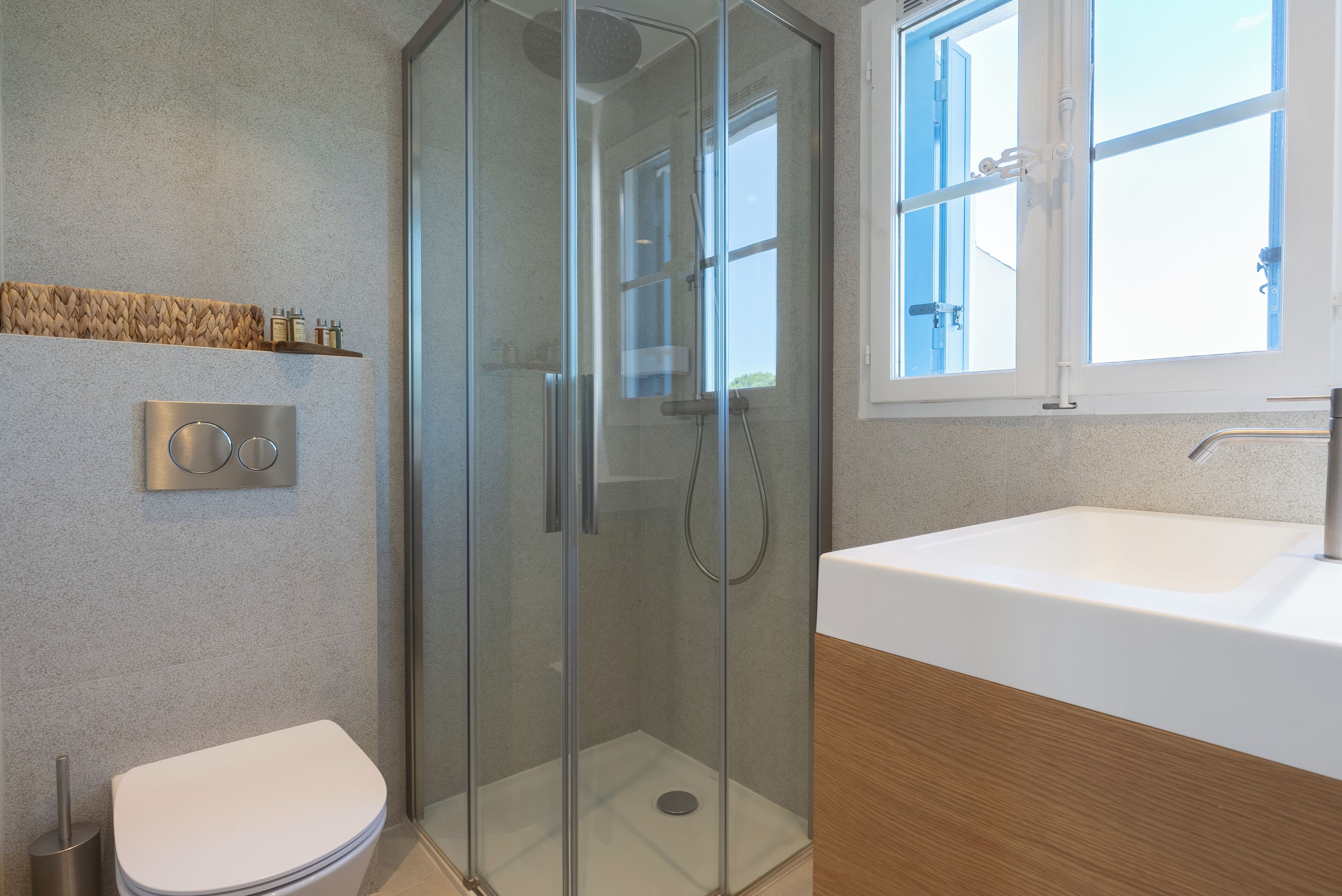A modern bathroom with a glass-enclosed shower, a white sink, and a toilet.