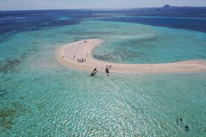 Vista aérea de uma praia com águas turquesa cristalinas e uma faixa de areia.