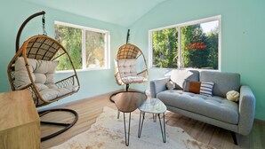 A room with two wicker chairs, a grey sofa, and a small table.