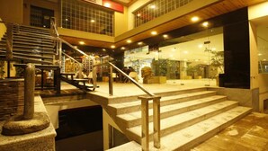 Interior com vários níveis, escada, degraus de pedra e fachada de vidro.