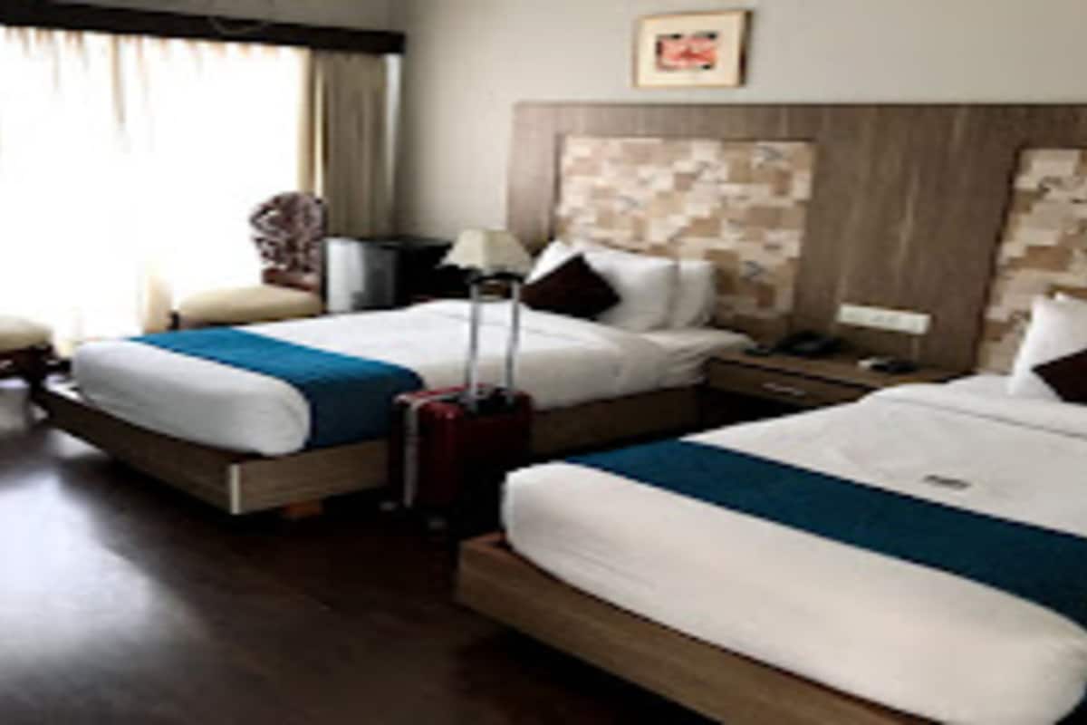 Ein Hotelzimmer mit zwei Betten, einem hölzernen Kopfteil, einem Schreibtisch und einem Stuhl.