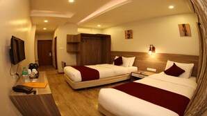 Quarto de hotel com duas camas, uma escrivaninha com televisão e um guarda-roupa.