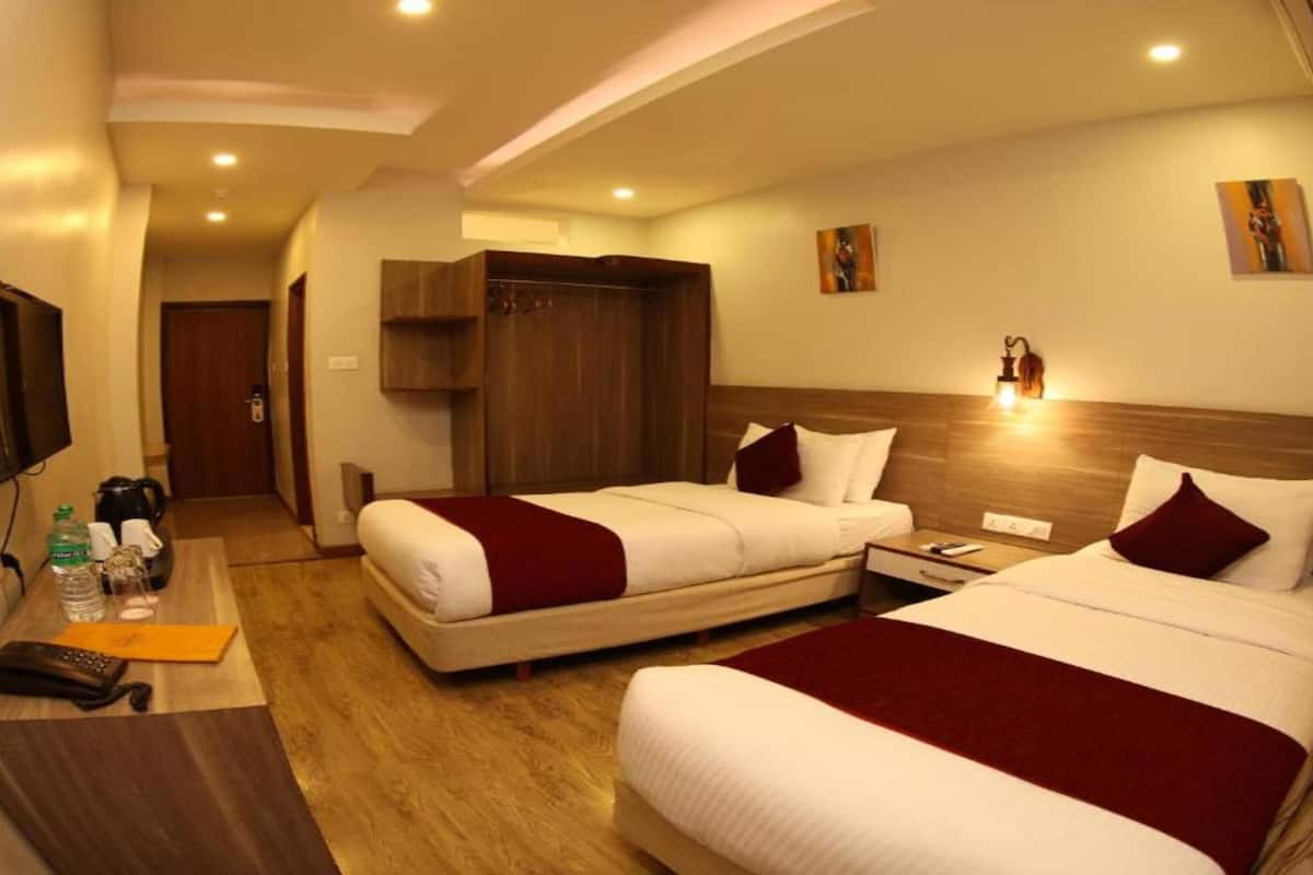 Ein Hotelzimmer mit zwei Betten, einem Schreibtisch mit Fernseher und einem Kleiderschrank.