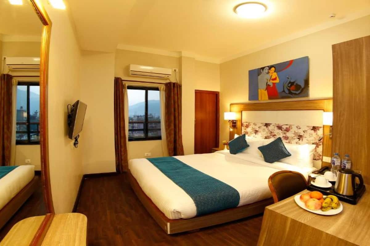 Ein Hotelzimmer mit einem Bett, einem Schreibtisch mit Obstplatte, einem Spiegel und einem Bild an der Wand.