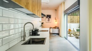 A modern kitchen with white tiles, a stainless steel sink, and wooden cabinets. - Spacious 3BR Apt w Garden Ramat Hasharon (Ramat Hasharon)