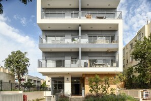 A multi-story residential building with balconies, a central entrance, and a small garden area. - Spacious 3BR Apt w Garden Ramat Hasharon (Ramat Hasharon)